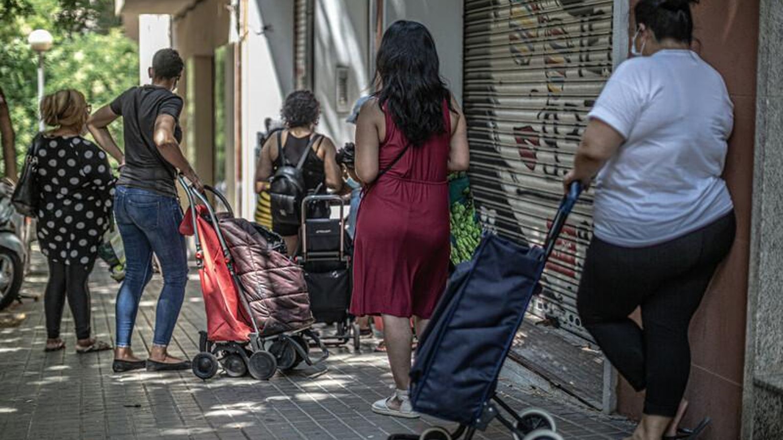 Un grup de dones fent cua en un punt de recollida d'aliments
