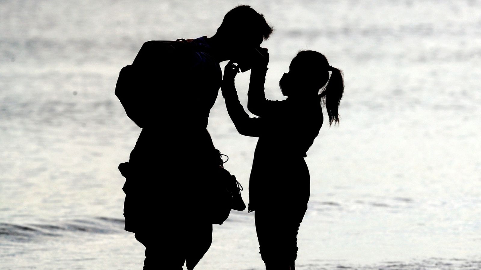 Una jove ajusta la mascareta a un jove vora mar, a la platja de la Malva-rosa de València aquest dijous