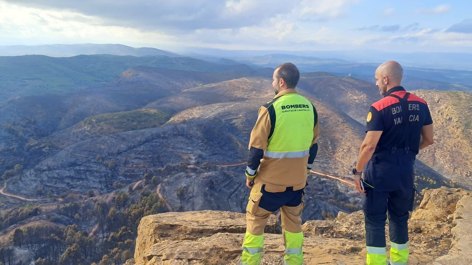Dos bombers, un del Consorci Provincial de Bombers de Castelló i altre del de València, comproven el resultat del pas de les flames a la Calderona des del pic de l'Àguila