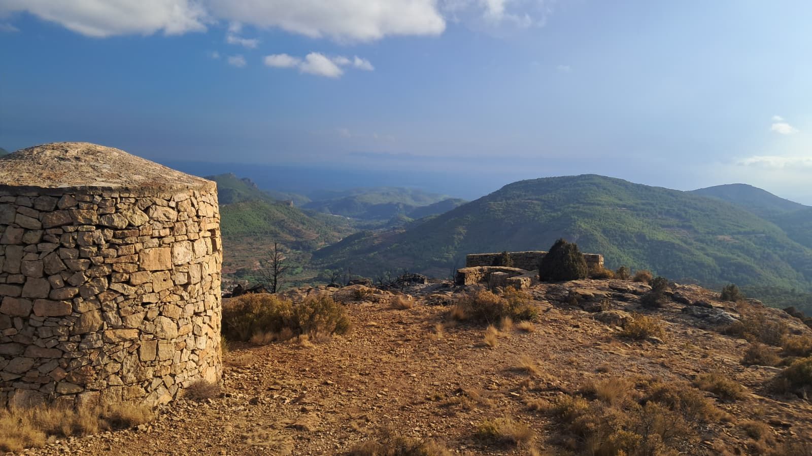 Paisatge de la serra Calderona afectat per l’incendi, amb vegetació i construccions de pedra en sec calcinades.