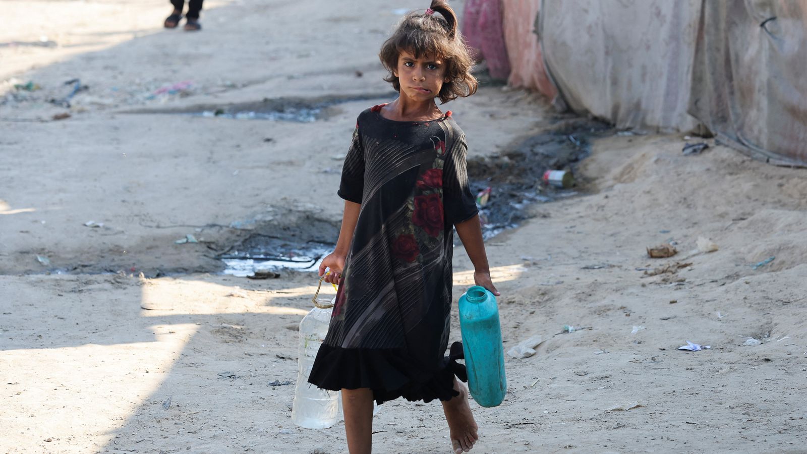 Una xiqueta palestina carrega bidons d'aigua a  Deir Al-Balah, en el centre de la Franja de Gaza