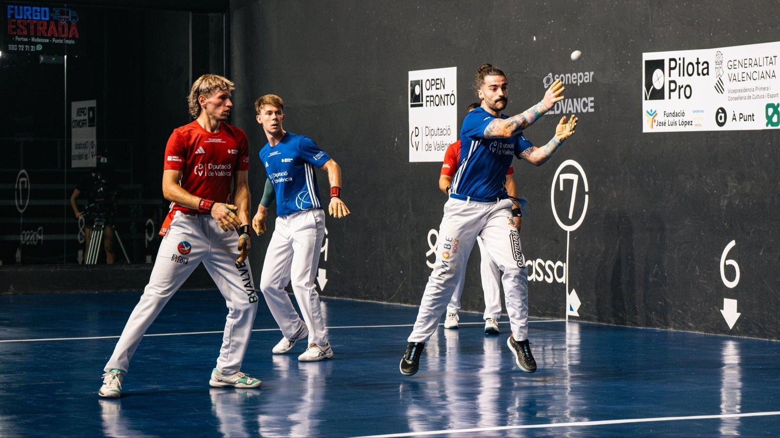 Adrián colpeja una pilota, davant l'atenta mirada del seu company Julio Palau, i el seu rival Saúl