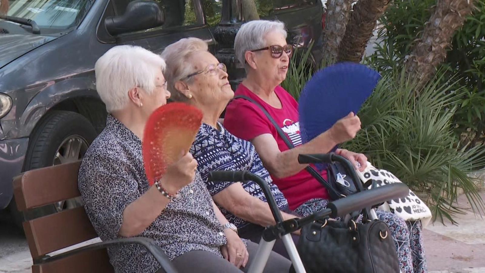 Tres dones al carrer combaten la calor amb ventall
