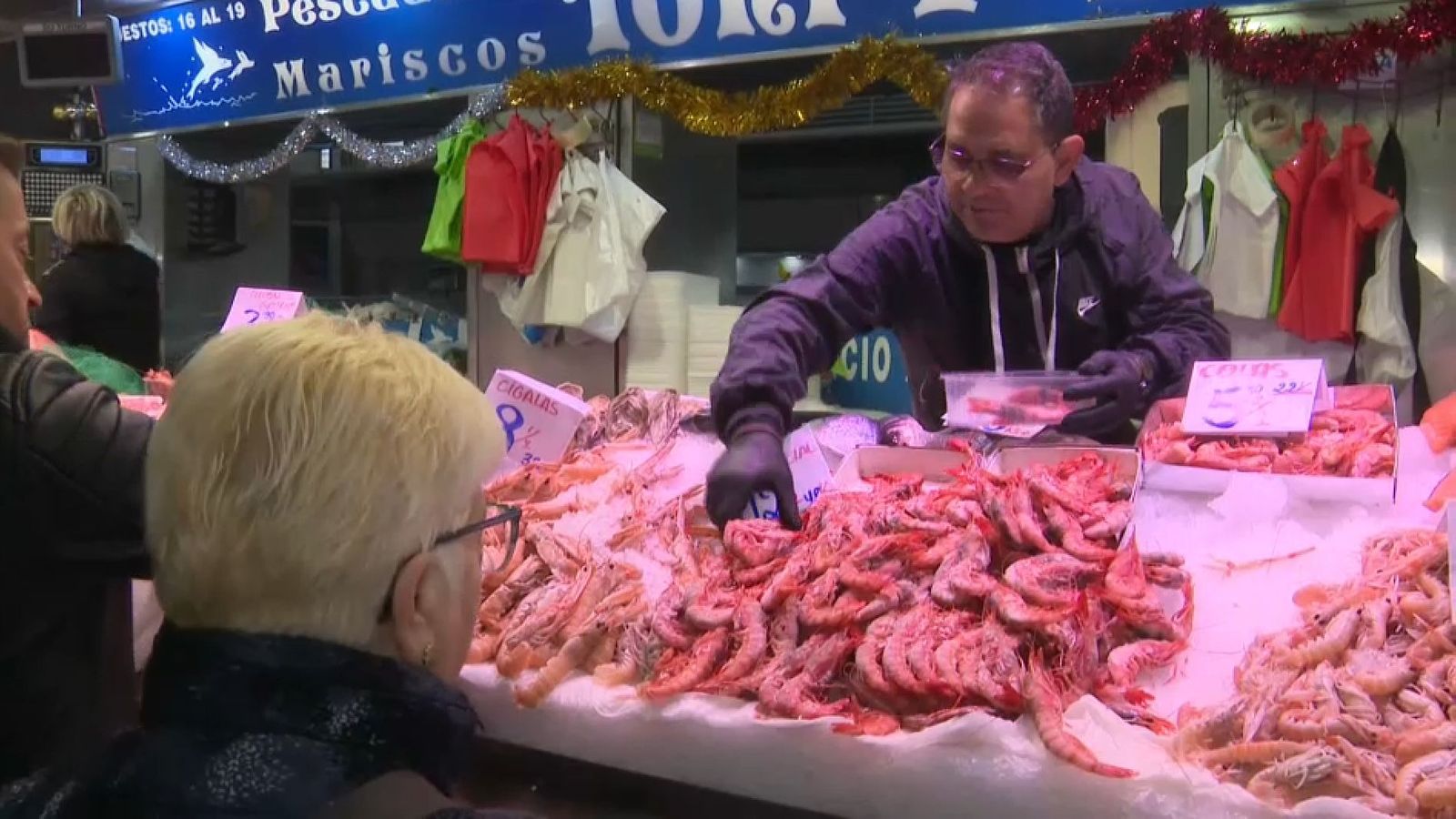 Un pescater del Mercat Central de València atén una clienta que este dimarts al matí comprava gamba, un dels productes estrela, del Nadal