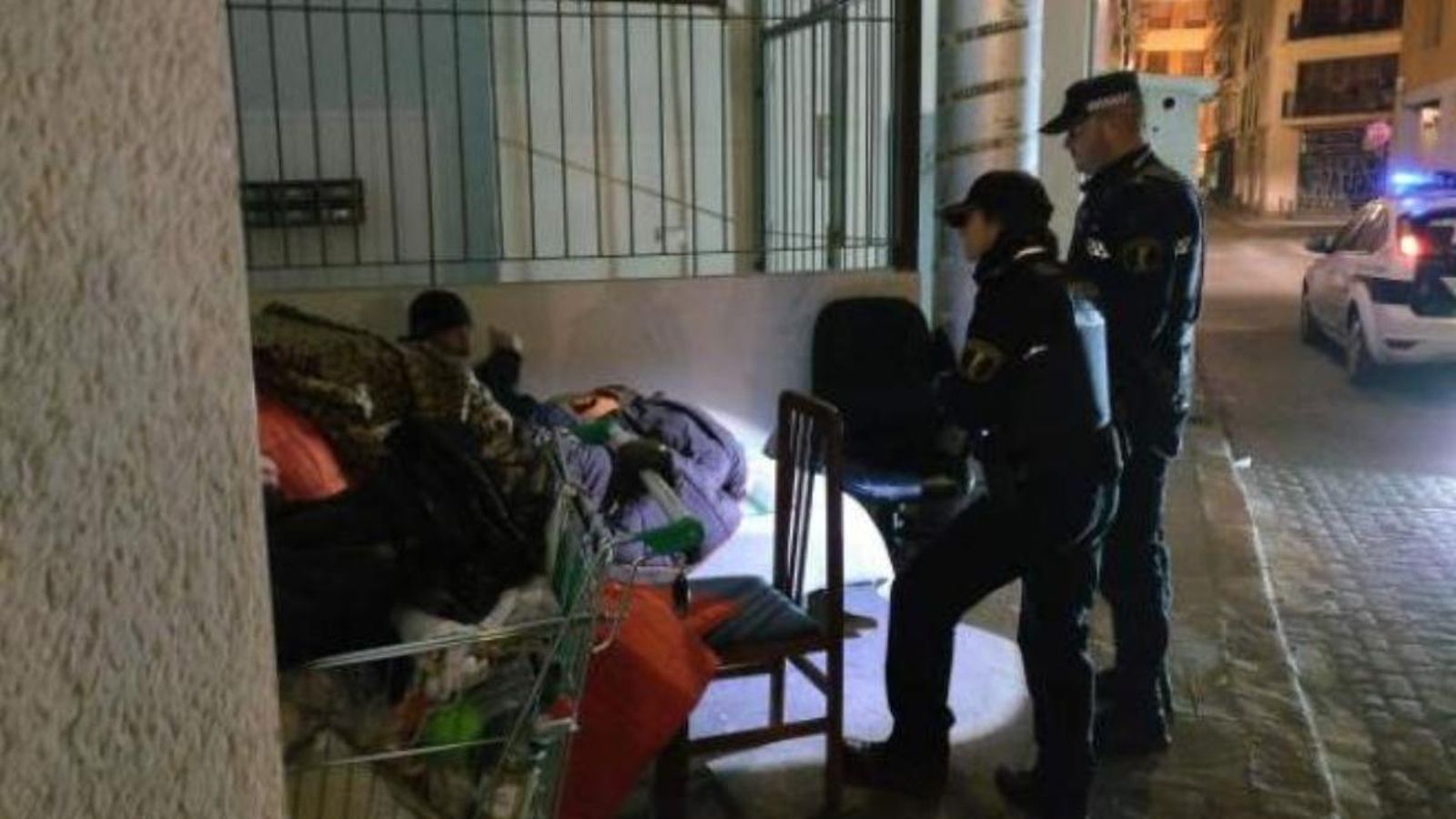Un agent de la Policia Local de València atén una persona sense llar en una imatge d'arxiu Un agent de la Policia Local de València atén una persona sense llar en una imatge d'arxiu