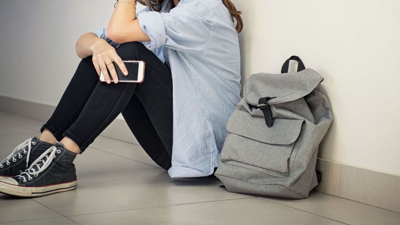 Una adolescent asseguda amb un telèfon mòbil / Ground Picture (Shutterstock)