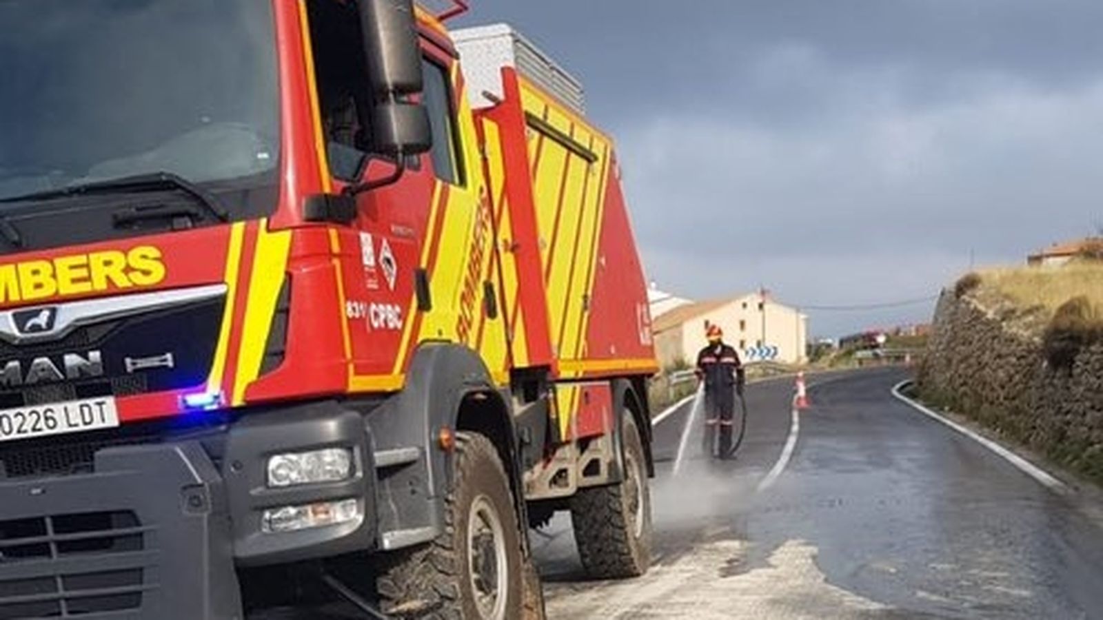 Els bombers treballen per netejar la carretera on s'ha produït el vessament de llot