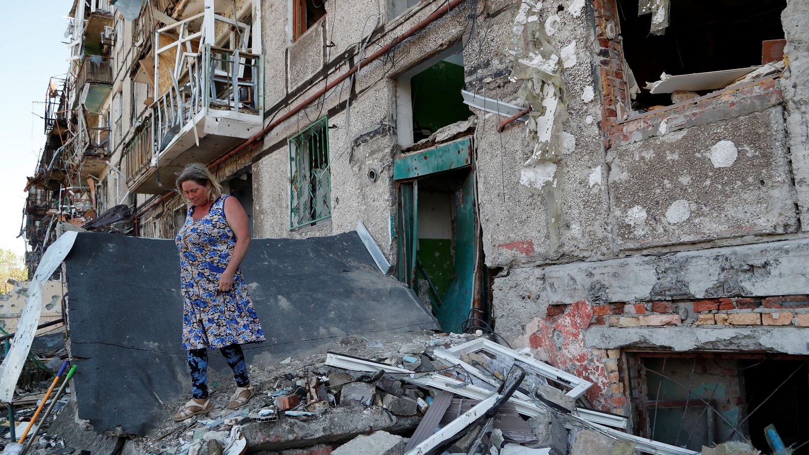 Una dona camina sobre enderrocs fora d'un edifici d'apartaments a Mariúpol, Ucraïna