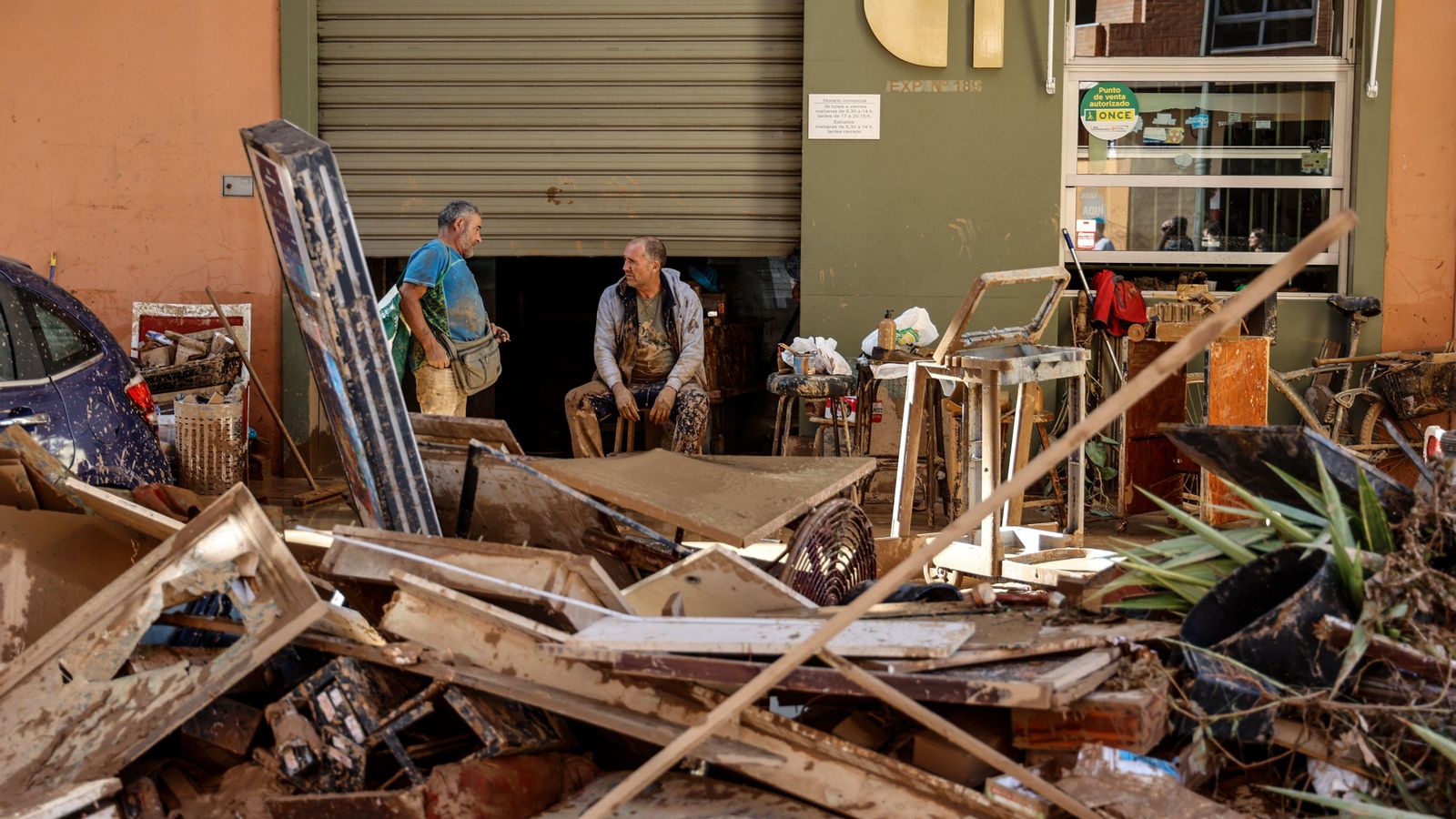 Dos veïns de la pedania de la Torre de València, conversen darrere d'un muntó de deixalles