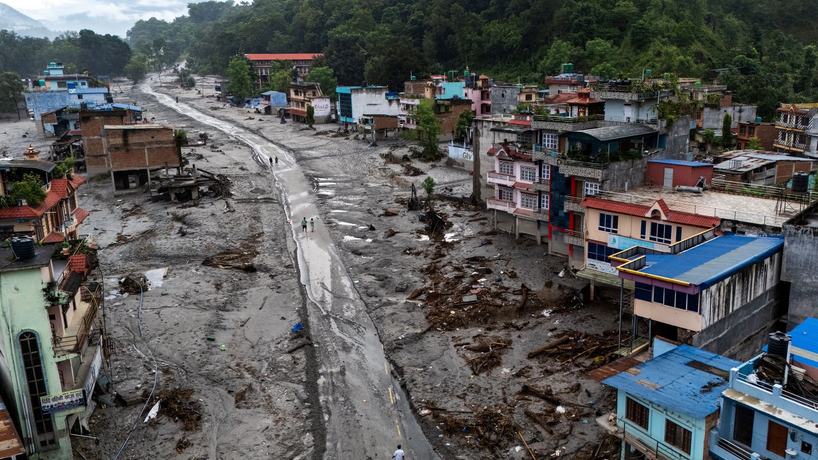 Una imatge captada per un dron al districte de  Nuwakot, a Nepal, mostra persones caminant sobre el fang en una població afectada per la riuada