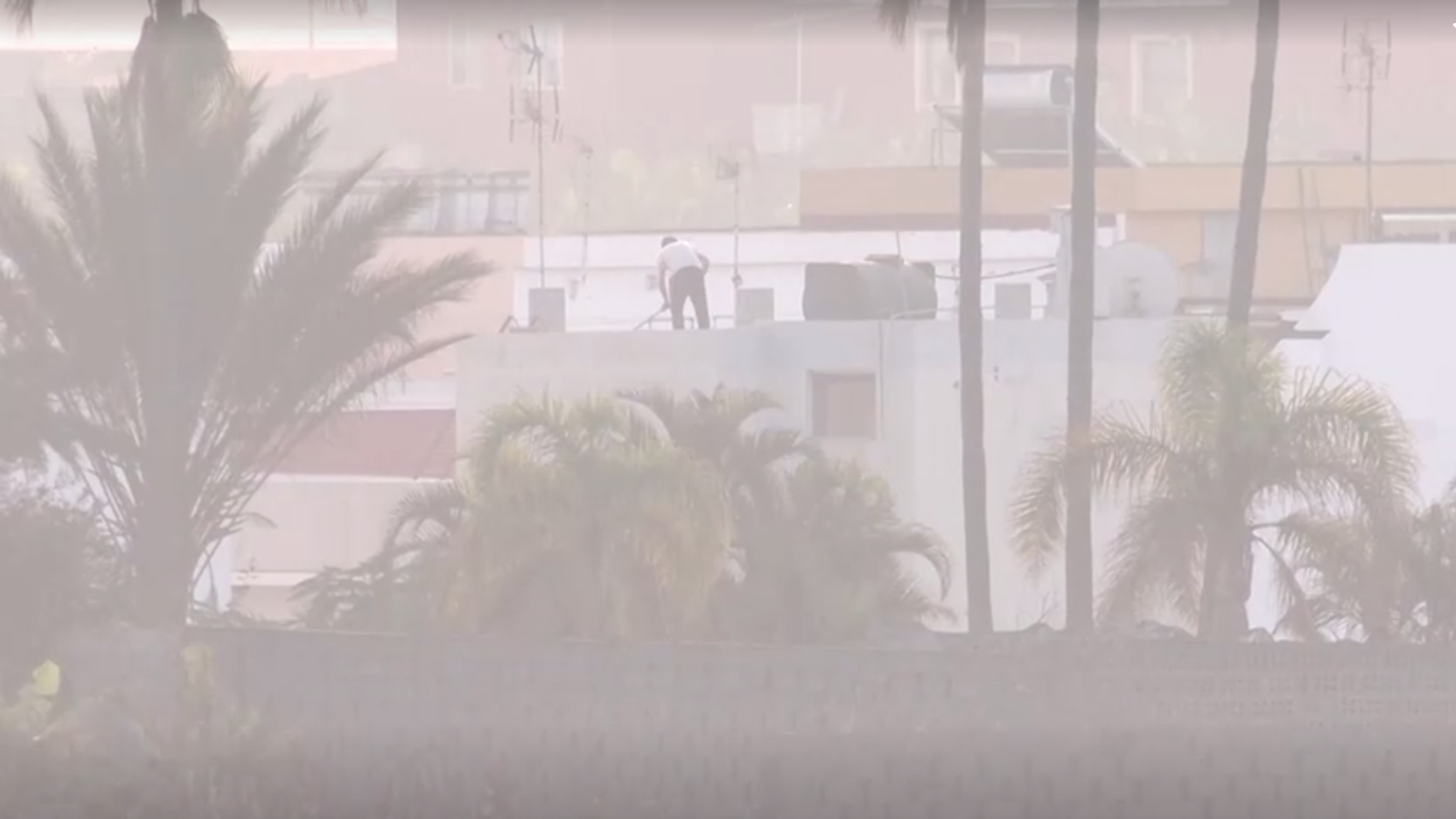 Una persona neteja la cendra volcànica d'edificis a La Palma