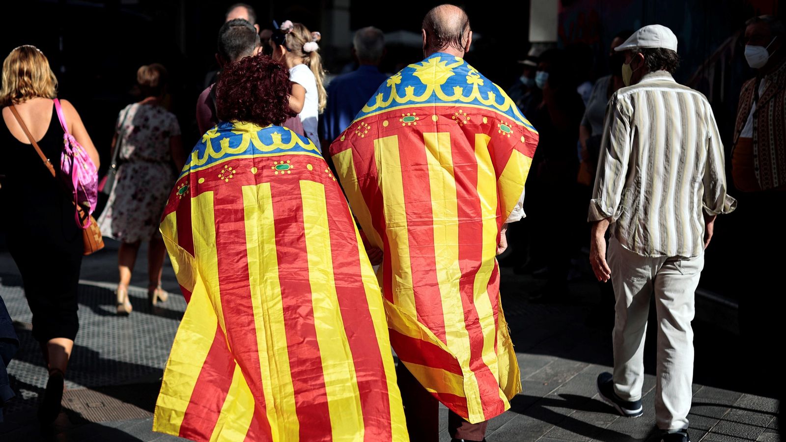Dues persones passegen per València amb una senyera a l'esquena