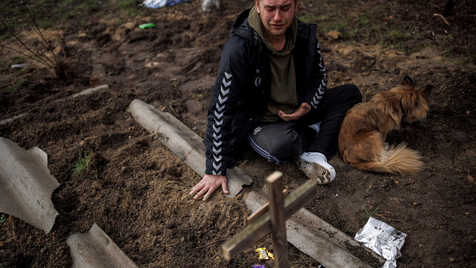 Un home plora davant d'una tomba a Butxa