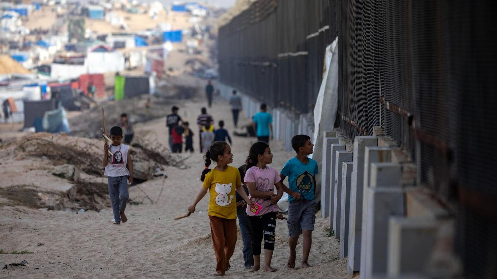 Xiquets palestins desplaçats caminen aquest dissabte al costat de la tanca fronterera amb Egipte, a Rafah, en el sud de la Franja de Gaza