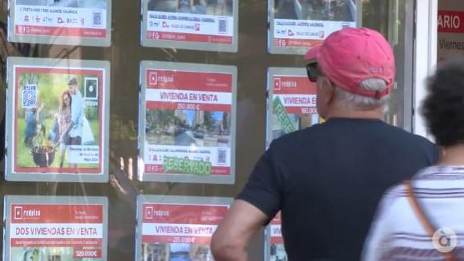 Un home mira preus d'habitatges en l'aparador d'una immobiliària Un home mira l'aparador els preus dels habitatges en una immobiliària