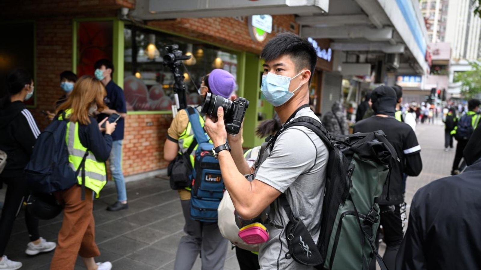 Un periodista treballa a Hong Kong amb mascareta i protecció contra el gas pebre