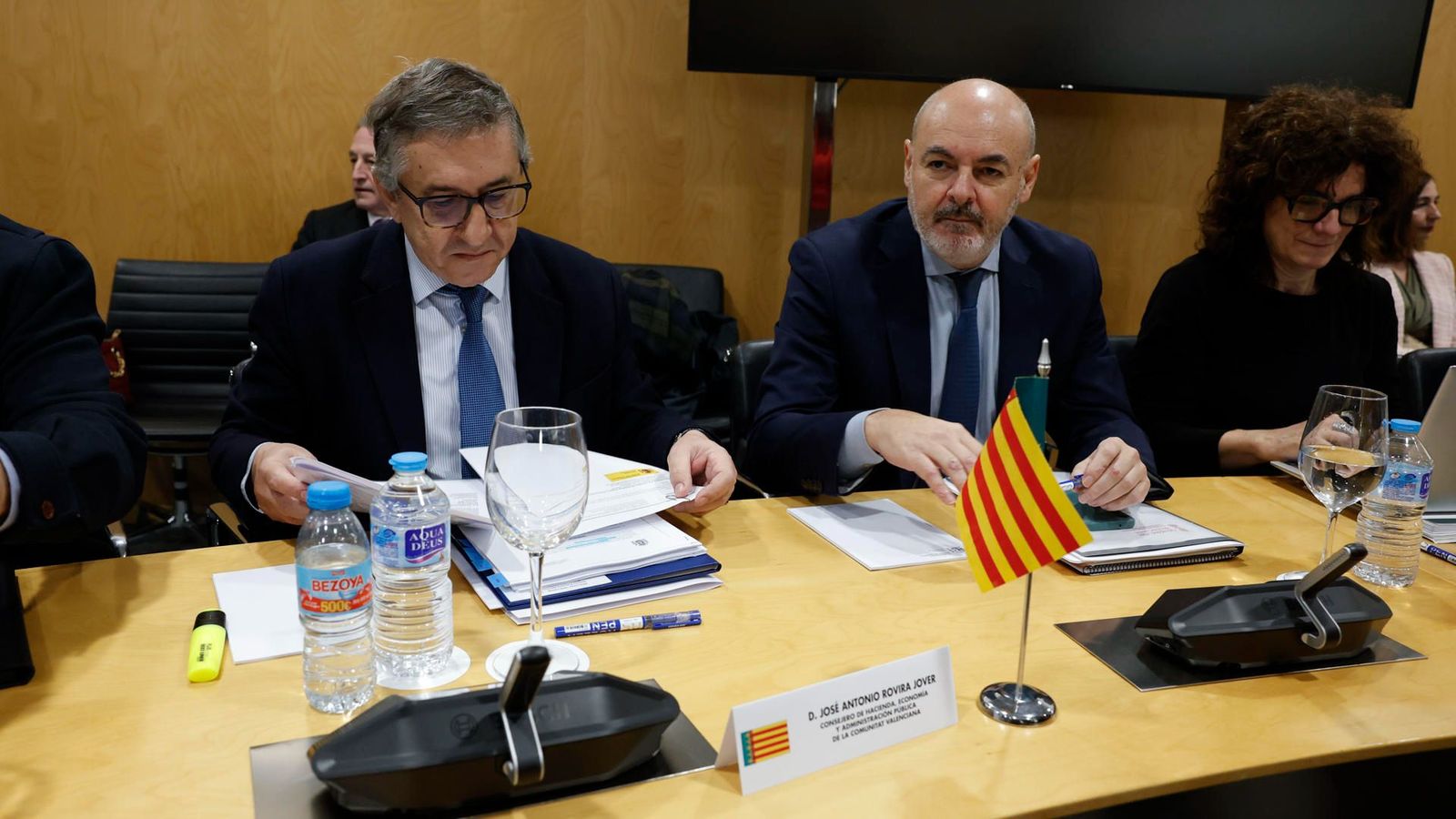 El conseller d'Hisenda, junt al secretari autonòmic d'Hisenda, fulleja un document durant la reunió del Consell de Política Fiscal i Financera