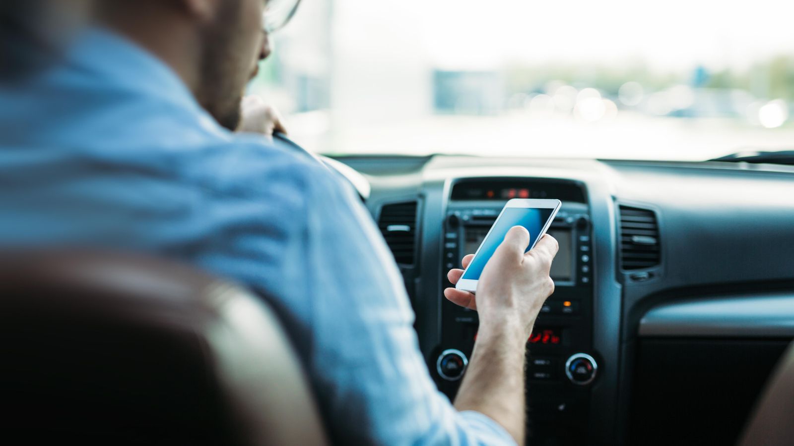 Un conductor atén el seu telèfon mòbil mentre condueix