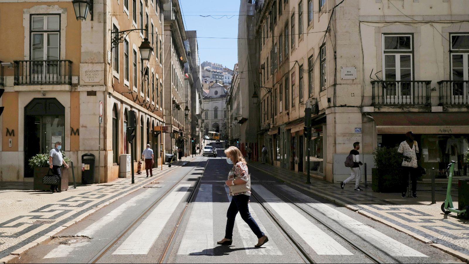 Una vianant amb mascareta creua el carrer a Lisboa