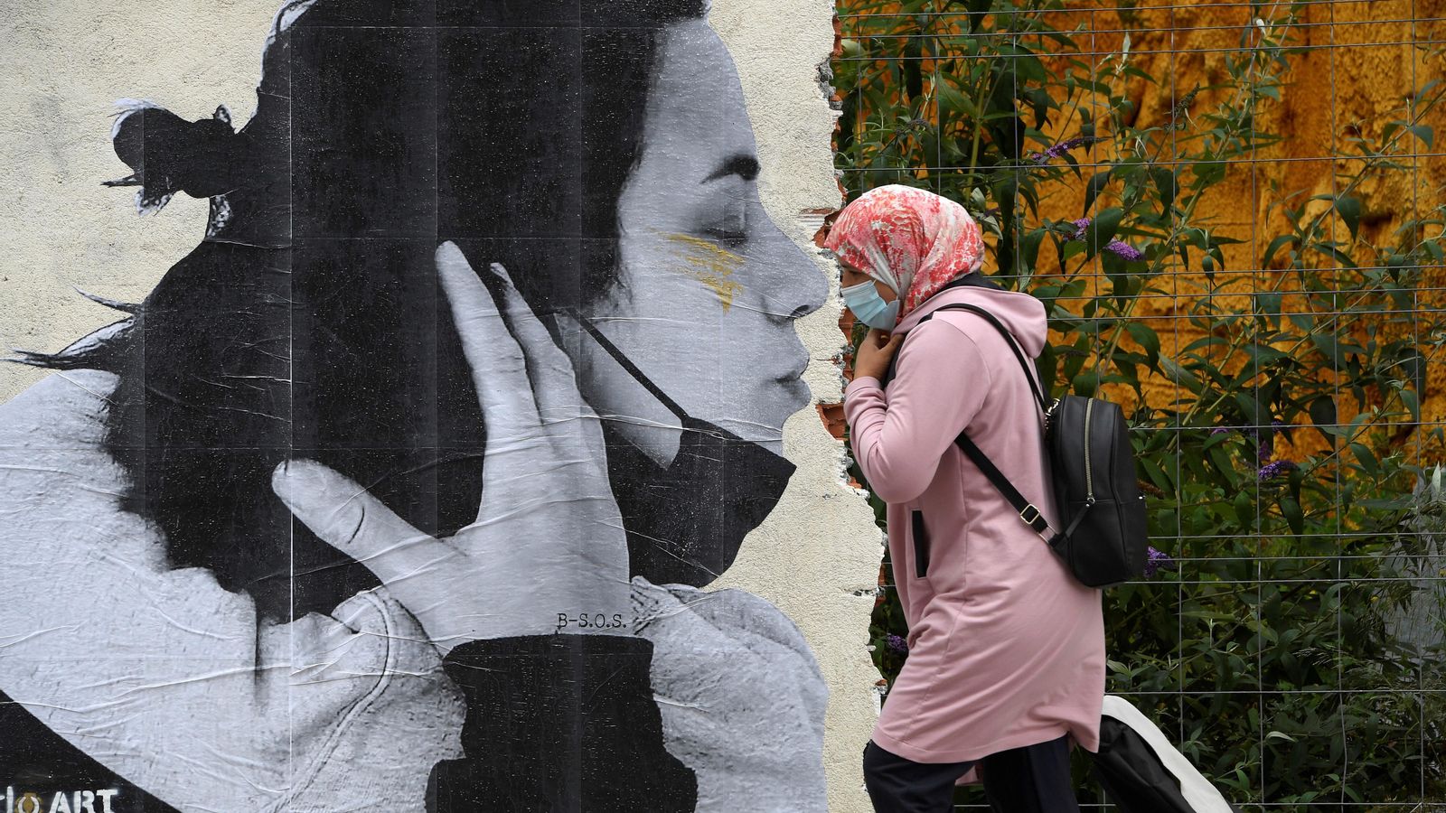 Una dona passa per davant d’un grafiti que l’artista Sentydo ha fet als carrers d’Oviedo per a reivindicar els besos sense mascaretes