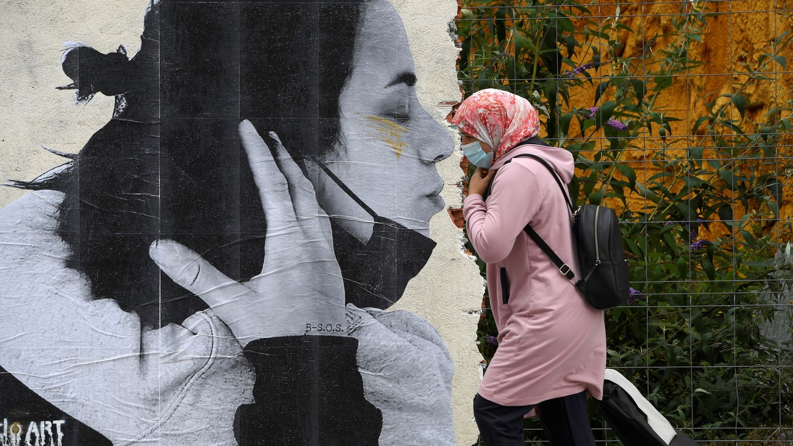 Una dona passa per davant d’un grafiti que l’artista Sentydo ha fet als carrers d’Oviedo per a reivindicar els besos sense mascaretes