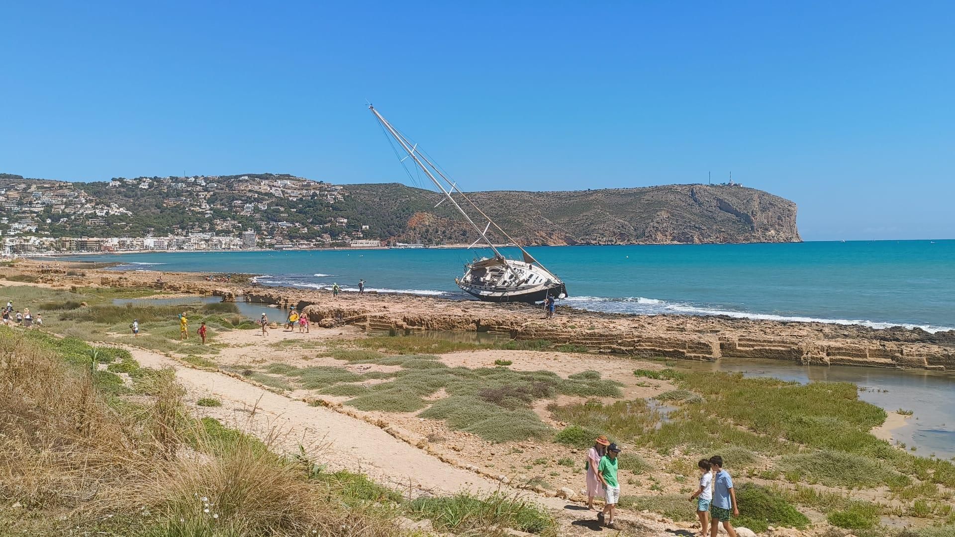 El veler continua encallat entre les roques de la platja Primer Muntanyar, davant la mirada de banyistes i curiosos que s’apropen El veler continua encallat entre les roques de la platja Primer Muntanyar, davant la mirada de banyistes i curiosos que s’apropen
