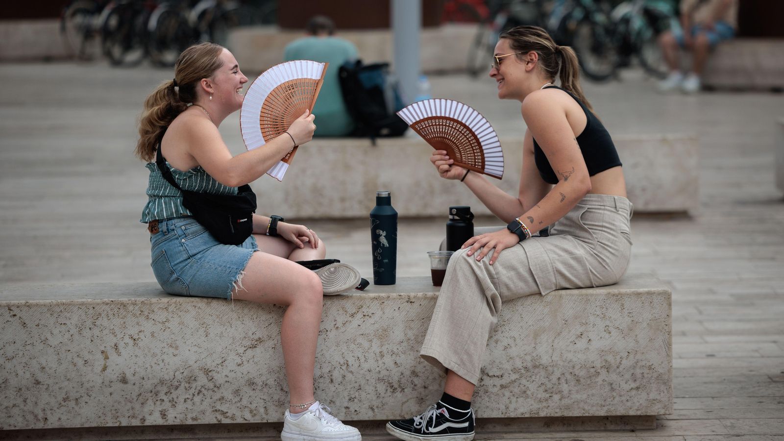 Dues joves combaten la calor amb ventalls Dues joves combaten la calor amb ventalls