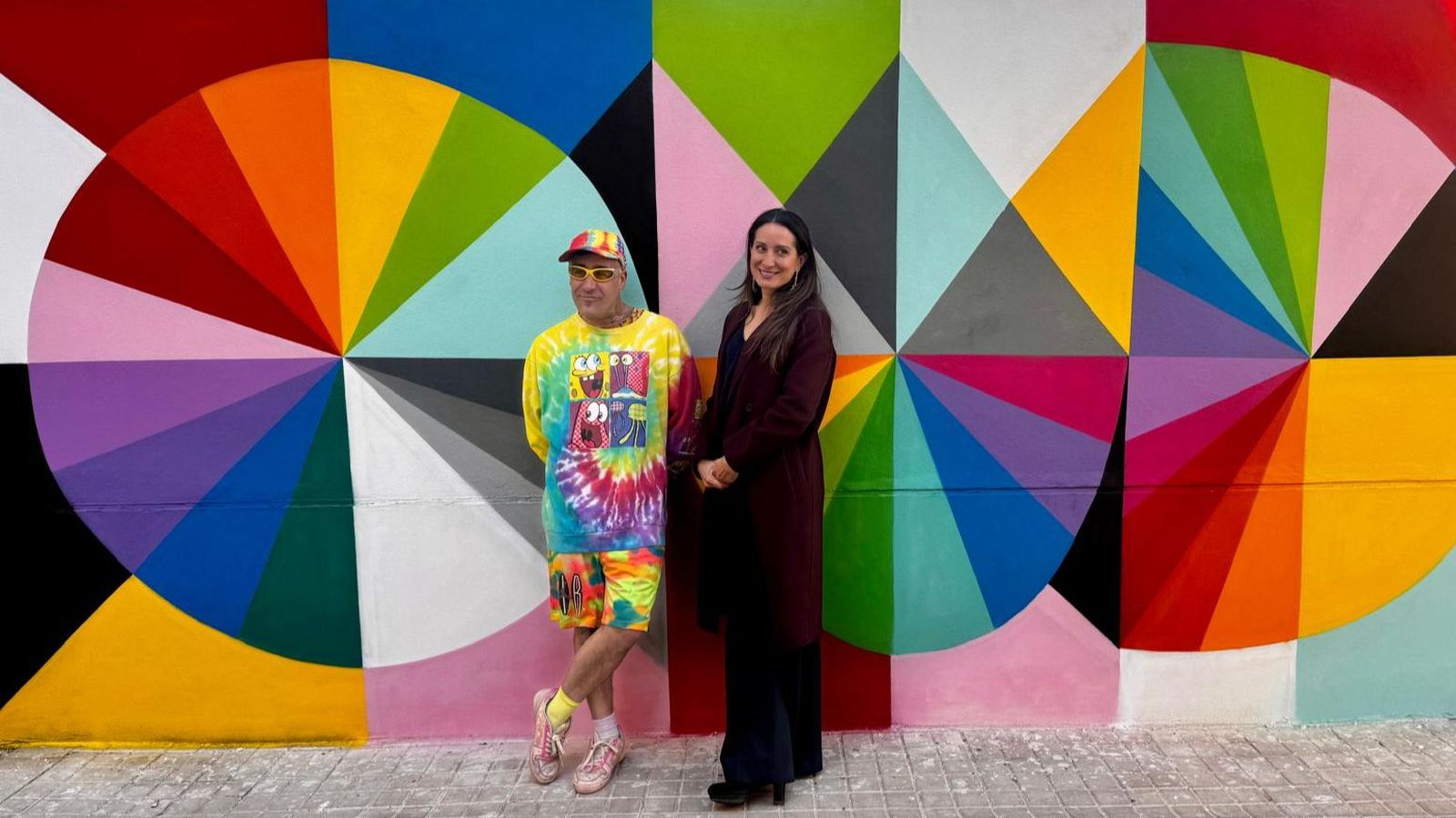 Okuda i Elena Sánchez, presidenta de Casa Caritat, davant una part del gran mur que ha pintat l'artista càntabre a l'escola infantil de La Petxina