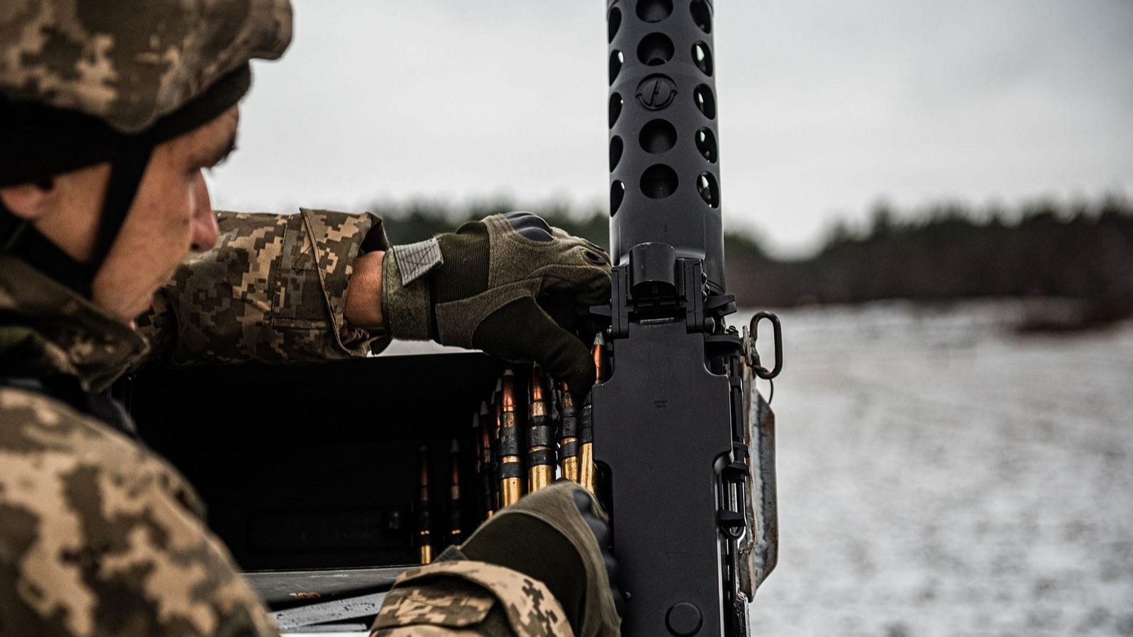 Un soldat ucraïnés posa les bales en la metralladora amb la neu al fons