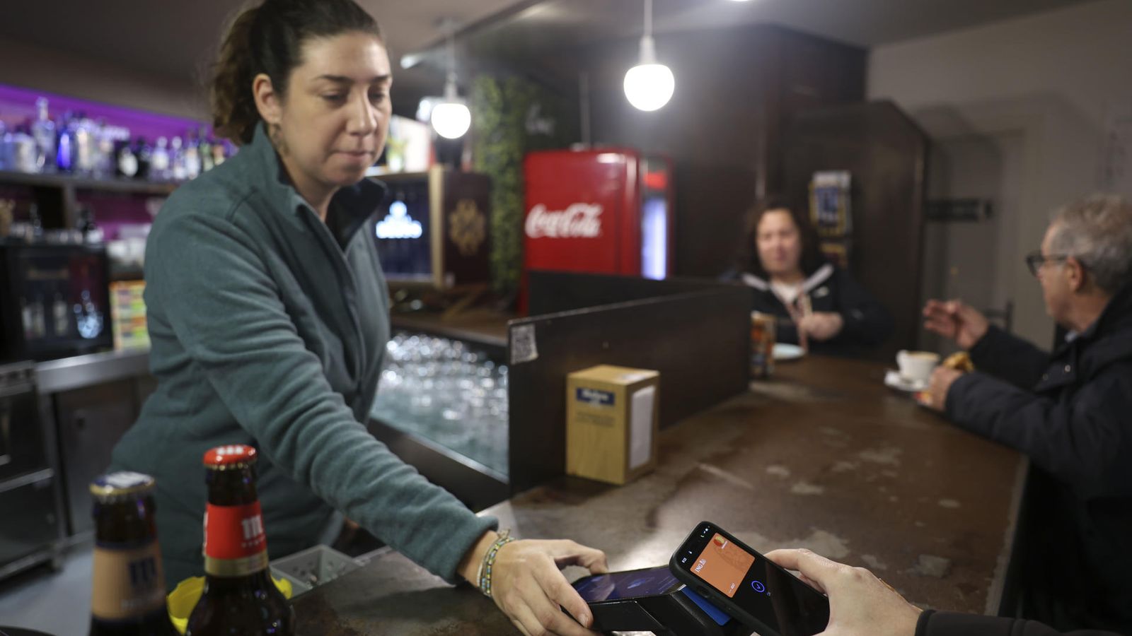Una cambrera cobra una persona en un bar