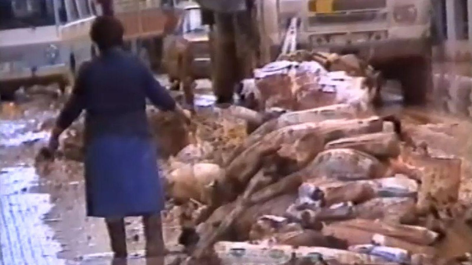 Una dona camina junt a muntons d'objectes personals trets pel veïnat a un cèntric carrer d'Alzira en una imatge del 1982