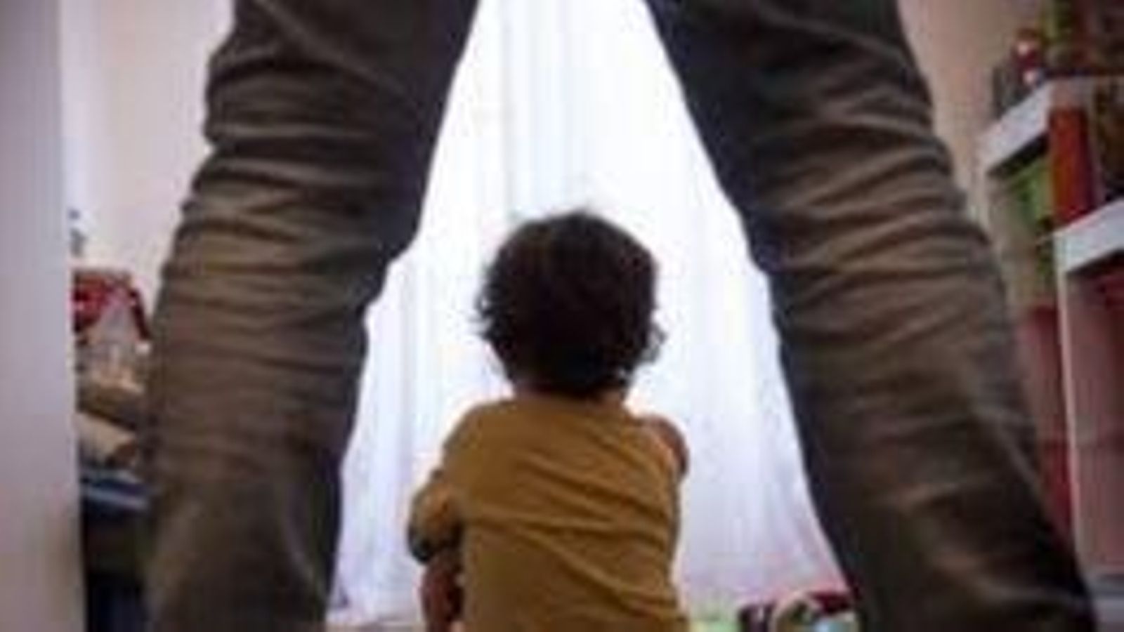 Un xiquet d'esquenas a un adult