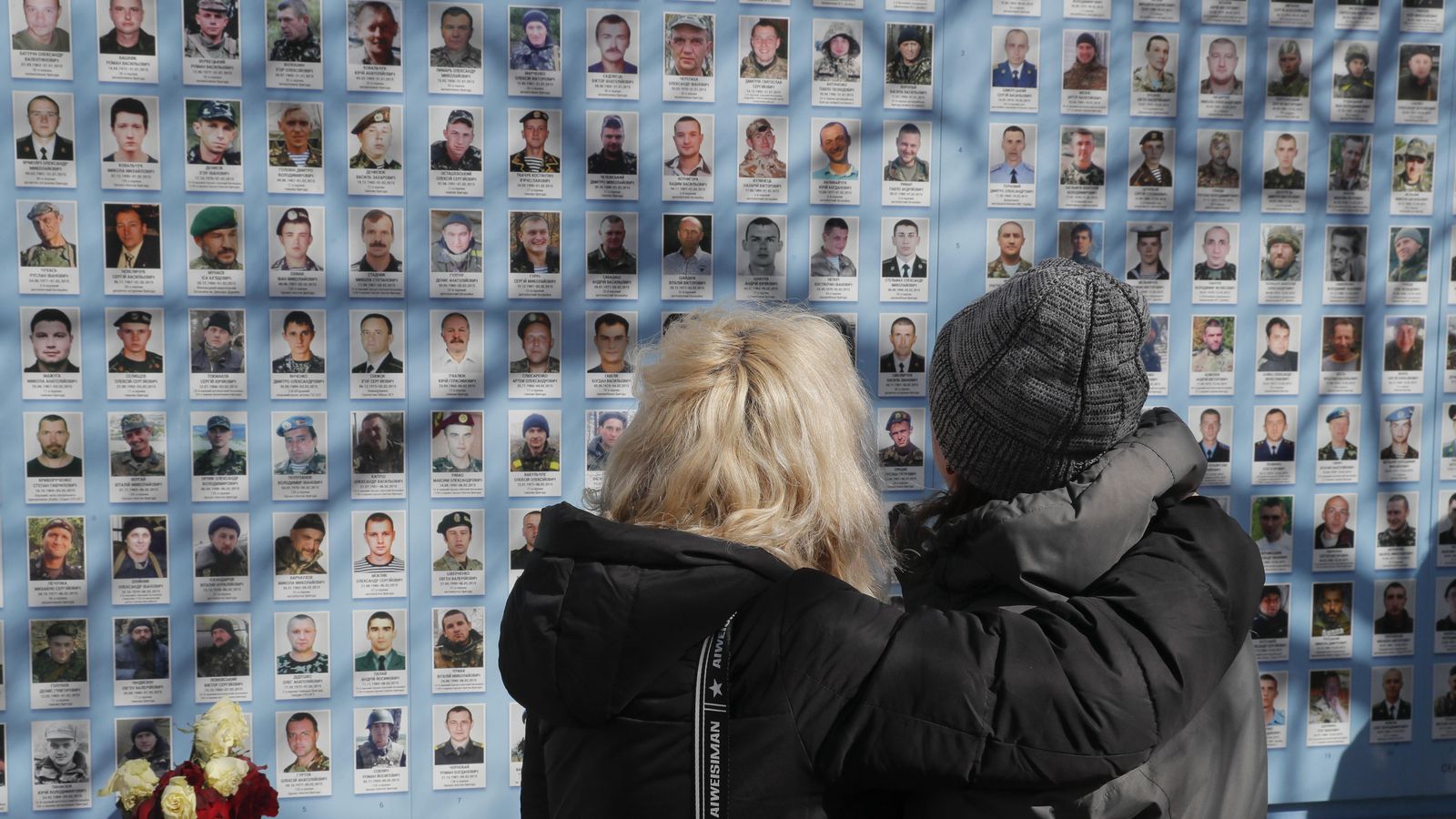Familiars i amics observen el Mur de la Memòria que commemora als defensors d'Ucraïna caiguts, prop de la Catedral de San Miguel a Kíiv