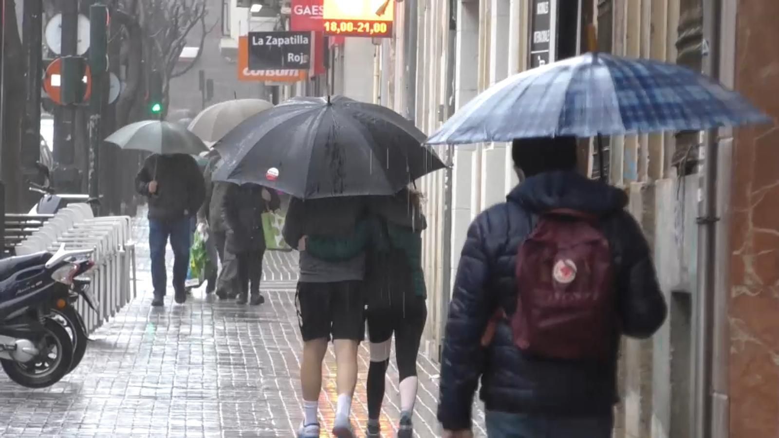Vianants es protegeixen de la pluja, en una imatge d'arxiu Vianants es protegeixen de la pluja
