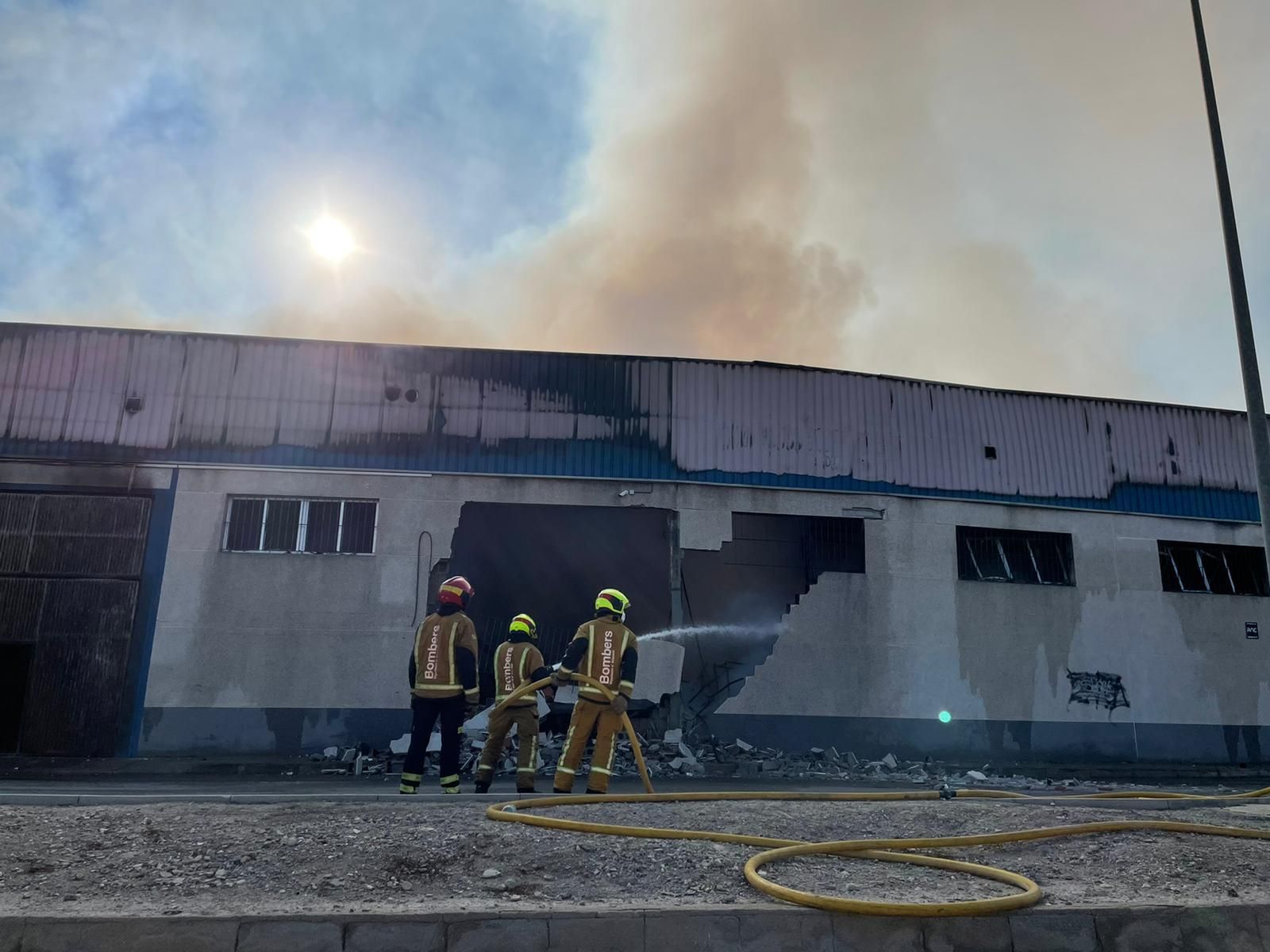 Aspecte exterior de la nau incendiada mentre treballen els bombers Aspecte exterior de la nau incendiada mentre treballen els bombers