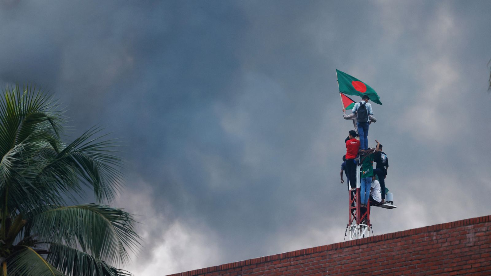 Manifestants onegen la bandera de Bangladesh a la residència de la fins ara primera ministra del país
