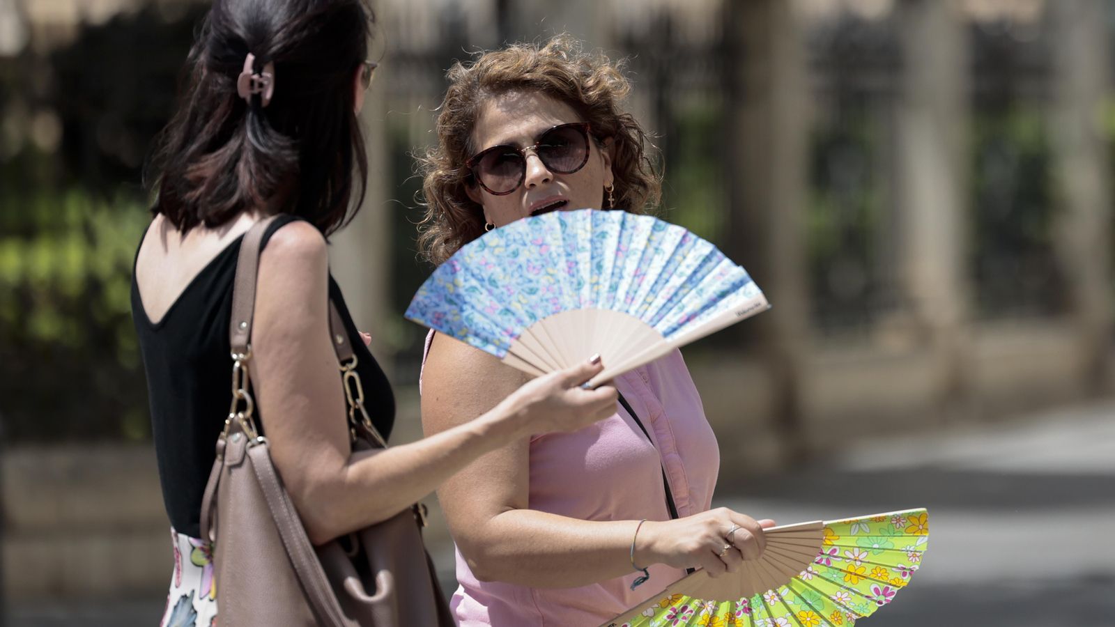 Dues dones es venten per a lluitar contra la calor Dues dones lluiten contra la calor amb ventalls