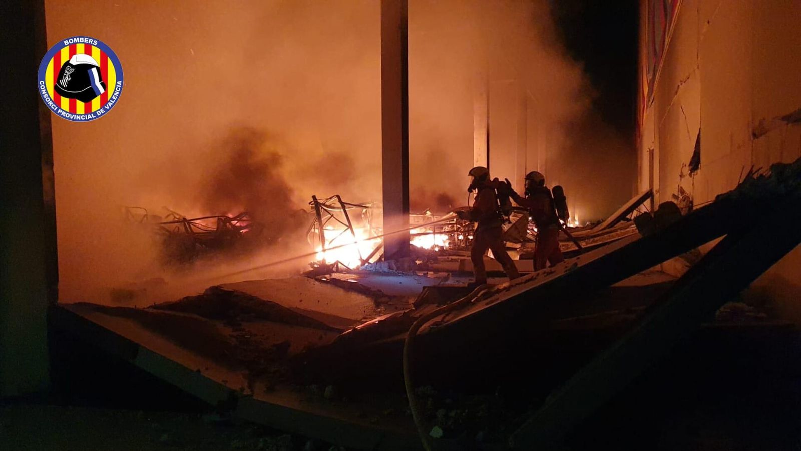 Dos bombers treballen en la nau d'Oliva on s'ha declarat l'incendi