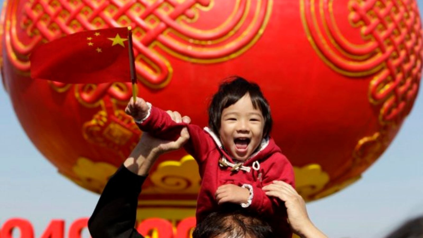 Un xiquet sosté la bandera xinesa a la plaça de Tiananmen