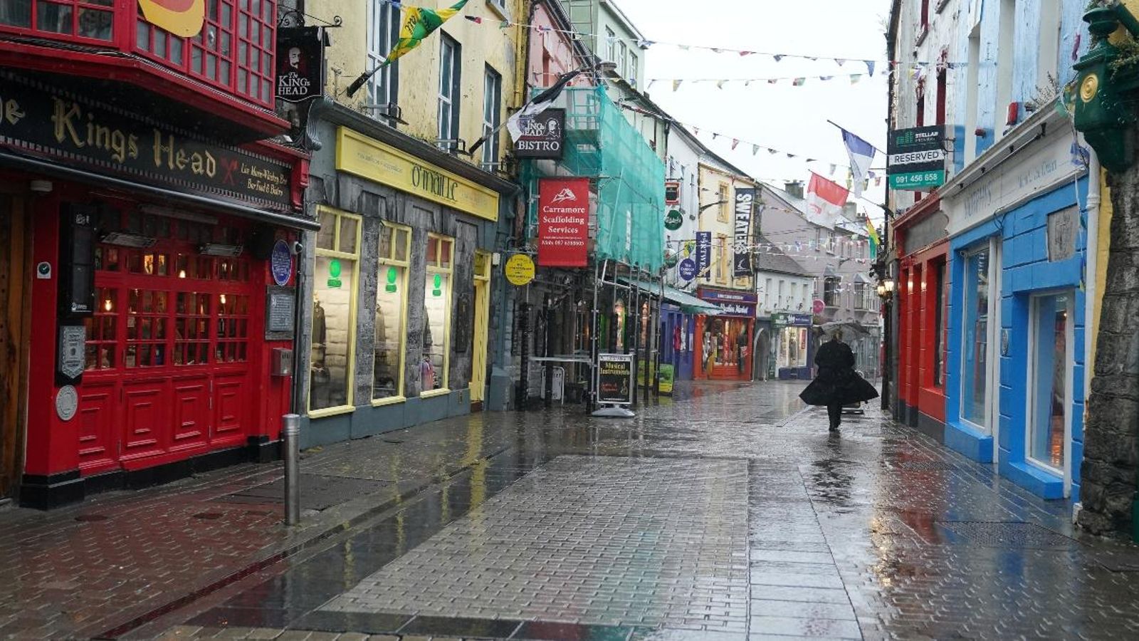 Una dona camina per un carrer comercial buit a Galway, Irlanda