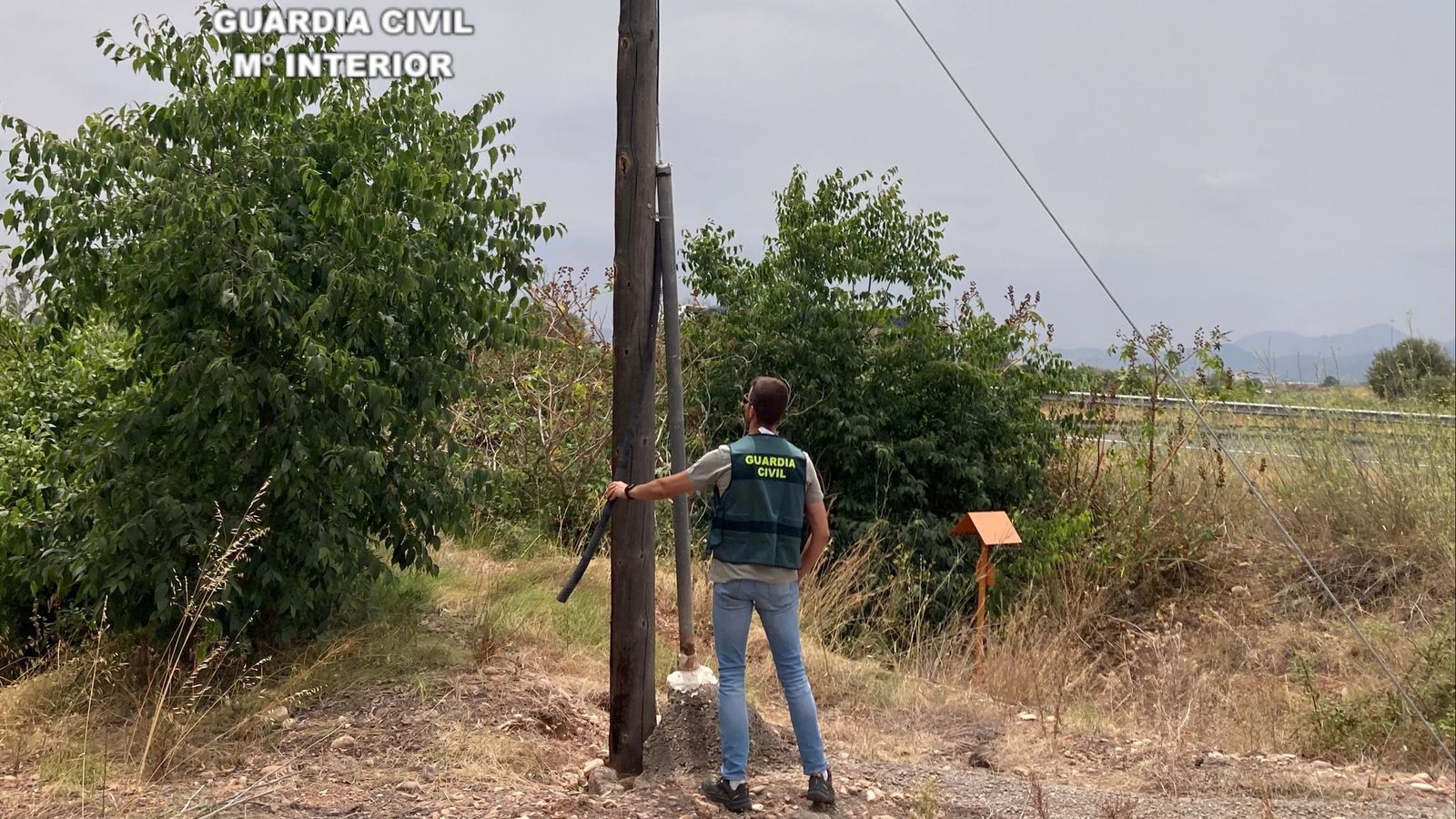 Un agent de la Guàrdia Civil junt a un dels pals del tram de cable de coure furtat