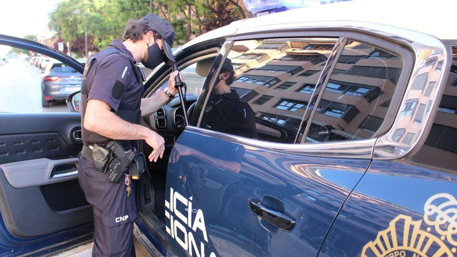 Un agent de la Policia Nacional al costat del seu cotxe patrulla