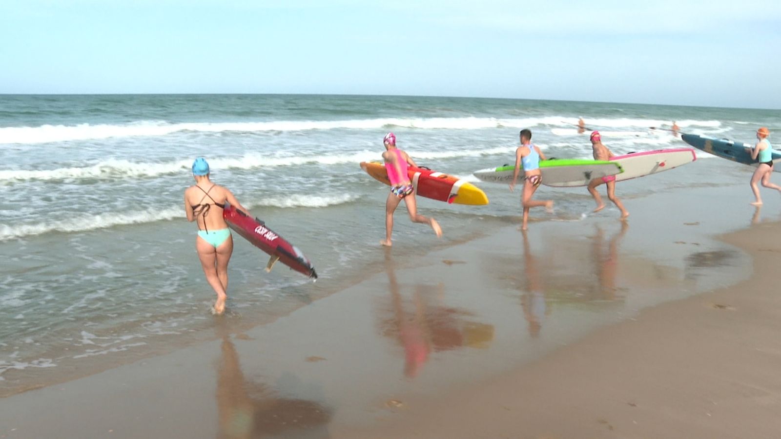 Un grup d'esportistes practica pàdel surf a la platja de València