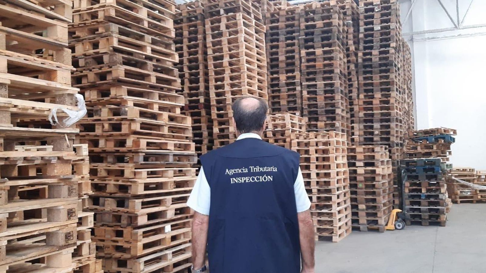 Un funcionari en un local de palés de fusta Un funcionari en un local de palés de fusta