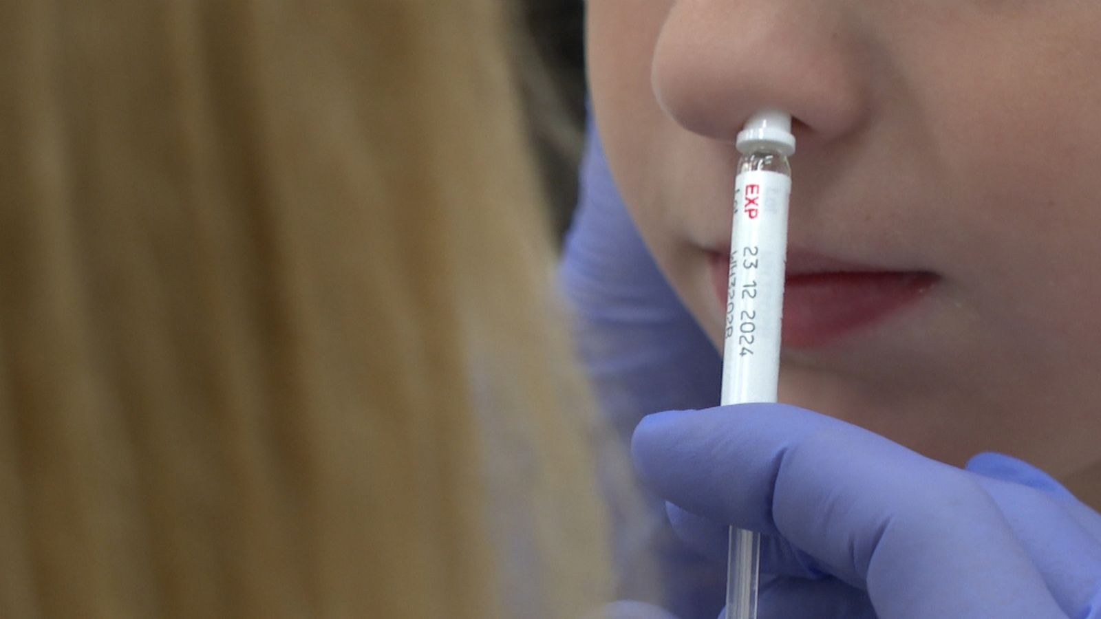 Una infermera administra la vacuna intranaslal contra la grip a un menor