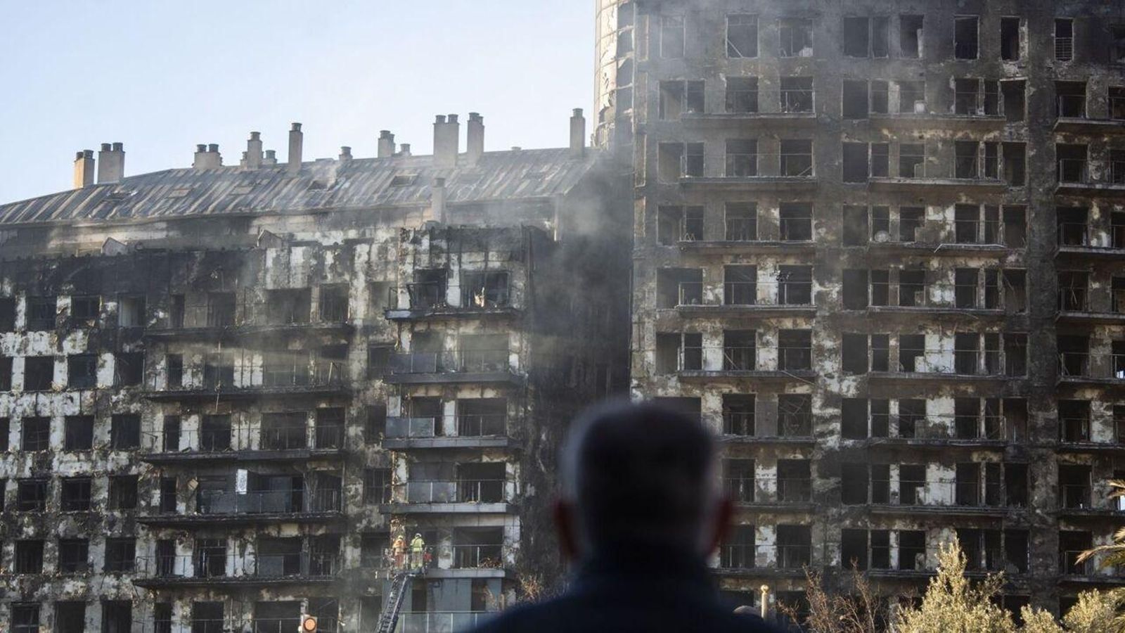 Un veí contempla les dues torres carbonitzades del residencial de Campanar, aquest divendres