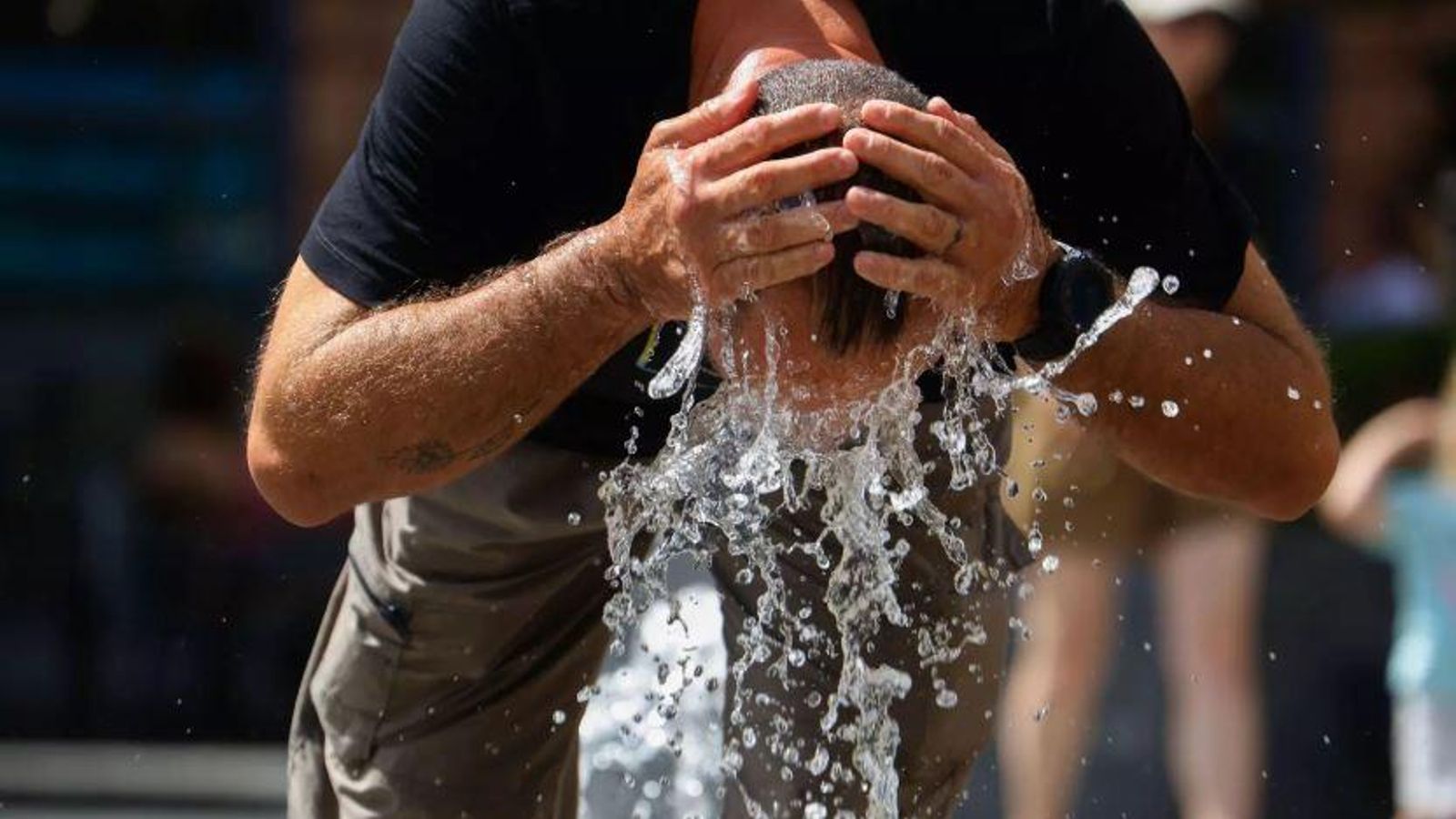 Un home es refresca en una font (EFE)