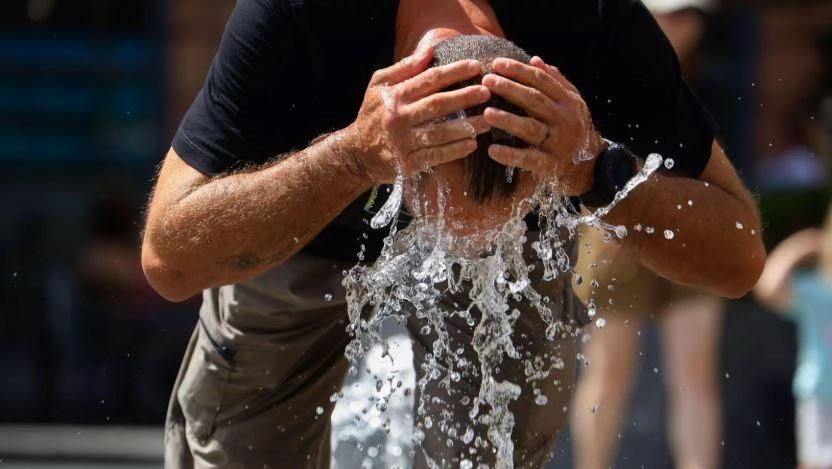 Un home es refresca en una font (EFE)