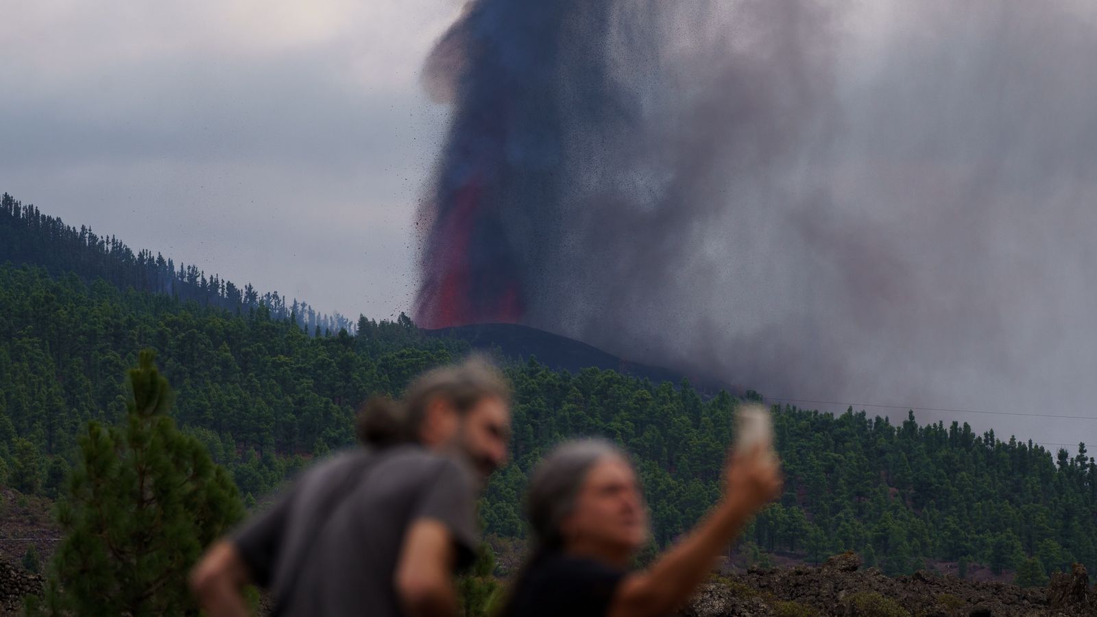 Una parella es fa una foto amb la gran columna de gasos que genera l'erupció del volcà de Cumbre Vieja