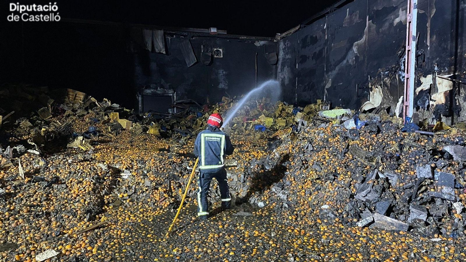 Un bomber treballa en la nau industrial calcinada a Almassora, on s'emmagatzemaven milers de quilos de cítrics
